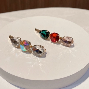 Detailed close-up of gold bobby pins with colorful teardrop and round rhinestones