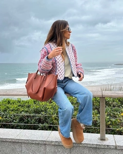 Pink floral quilted jacket styled with a brown leather tote and boots by the sea