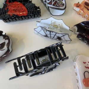 Detail view of Halloween hair claws featuring spider webs, hearts and pumpkin patterns