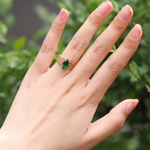 Detail of elegant gold triple band ring with marquise-cut green zircon on model hand