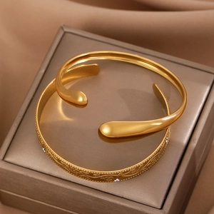 Detail of gold floral embossed bangle with white zircons on champagne satin background