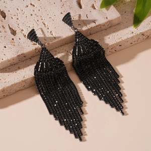 Détail de boucles d'oreilles à pompons noirs en éventail sur pierre texturée