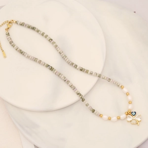 Detailed macro view of 18K gold-plated clover pendant with pearl and bead necklace