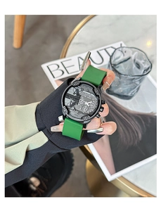 Detail of a large black dial quartz watch with green silicone strap on a male wrist