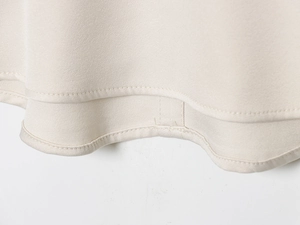 Detailed macro view of the cream-colored hemline showing fine twill cotton fabric texture