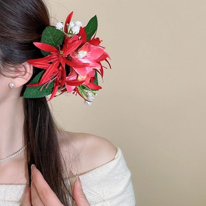 Detail of red and pink fabric flower hair clip worn elegantly on model's head
