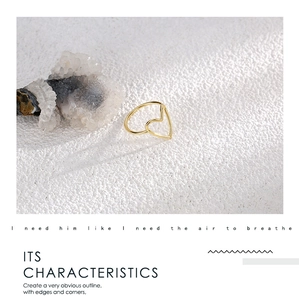 Detailed close-up of a minimalist hollow heart gold ring on a white textured stone surface
