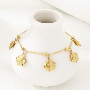 Close-up of golden tropical fish charms and fine chain on a white ceramic display