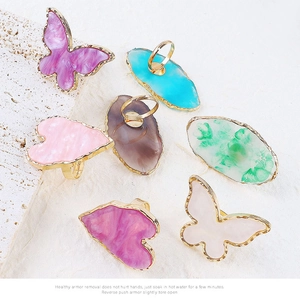 Vista de anillos de resina de colores con mariposas sobre textura de piedra