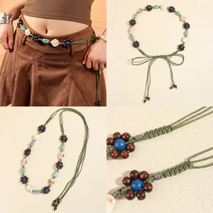 Detail of woven green waist chain featuring turquoise flowers, wood beads, and shell charms