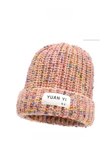 Close-up of pink knit beanie showing thick yarn texture and woven rectangular label