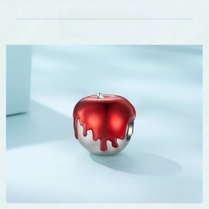 Detailed view of red and silver apple charm pendant with enamel glaze and metallic finish