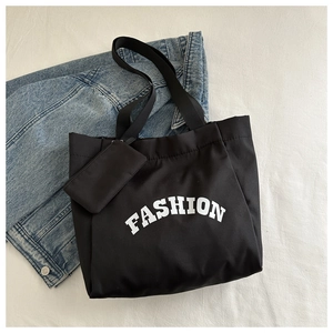 Close-up of black Oxford cloth tote bag with FASHION lettering and small hanging pouch