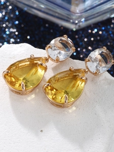 Macro shot of gold drop earrings with yellow pear-cut and clear oval crystals