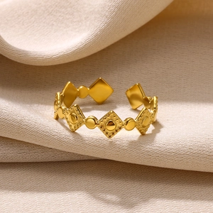 Close-up of golden geometric open ring with embossed diamond and dot texture details