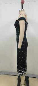 Détail de robe noire à épaules dénudées avec perles blanches et coupe ajustée sur mannequin