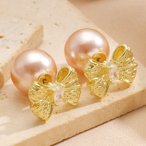 Detailed close-up of C-shaped bow pearl earrings on a premium stone and silk background
