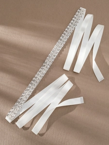 Close-up of bridal belt featuring intricate crystal and pearl embroidery on white satin ribbon