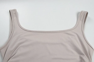 Détail du col carré et de la texture en maille élastique de cette robe moulante