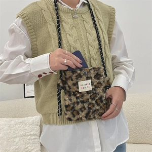 Detail of leopard print plush crossbody bag with woven rope strap and brand label