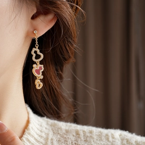 Detail of long gold dangling earrings with three wulu charms and red enamel accents