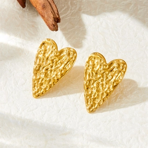 Gold heart stud earrings with hammered metal texture in a high-quality artistic display