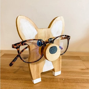 Detail of wooden corgi dog eyeglass stand holding tortoiseshell glasses on desk