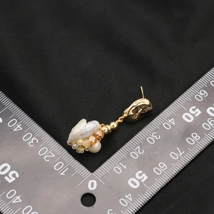 Baroque natural pearl drop earrings with 18k gold plating on black textured fabric