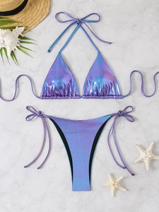Flat lay of holographic metallic bikini set with seashells and starfish on marble background