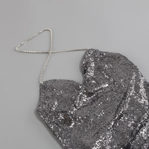 Détail d'un top dos nu à paillettes argentées avec chaînes en métal serties de strass