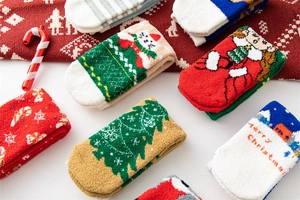 Flat lay of festive Christmas fuzzy socks with reindeer and tree patterns on red background