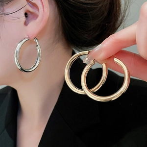 Detail shot of large polished thick hoop earrings in classic gold and silver finishes