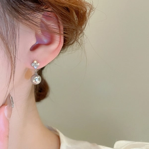 Close-up of elegant four-leaf clover earrings with zircon inlay and grey pearls on model