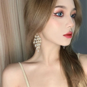 Macro shot of gold chandelier drop earrings with clear crystal droplets on model