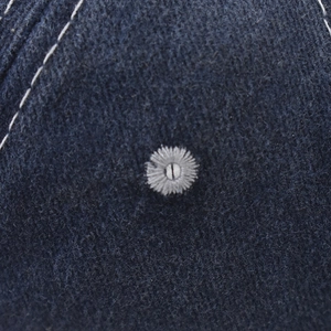 Détail macro de la broderie marguerite blanche sur la casquette de baseball bleu marine