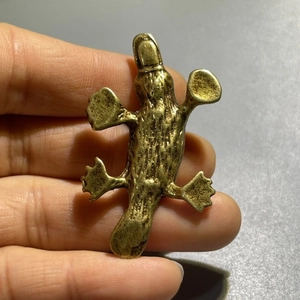 Vintage brass platypus figurine ornament held by hand to show compact portable size