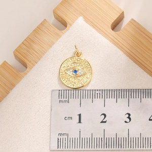 Detailed close-up of blue evil eye pendant with cubic zirconia on a 1.5cm measuring scale