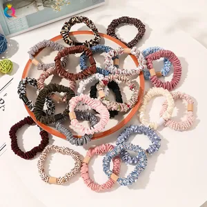 Close-up of assorted fabric scrunchies with square buckles on a white display stand