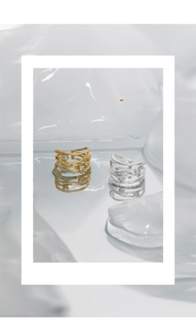 Macro shot of silver and gold layered textured rings with zircon accents on ice