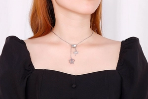 Gros plan du collier en acier titane argenté avec pendentifs libellule et papillon au cou