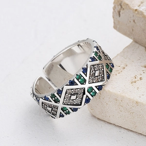 Macro shot of silver wide open ring with colorful gemstones on textured stone background