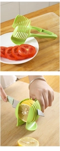 Manual green slicer holder for cutting lemon and tomato slices on wooden board