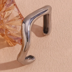 Macro shot of silver liquid wave bangle with a polished finish and open design
