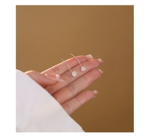 Detailed view of silver rose tassel earrings with iridescent white petals on a hand