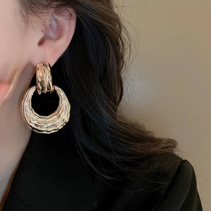 Detailed view of large gold vintage textured earrings with an irregular molten metal design