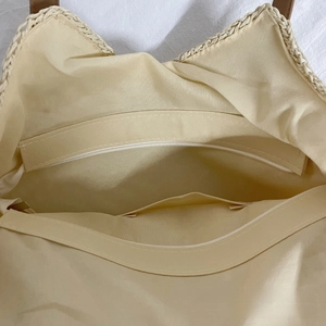 Detailed interior of the woven shoulder bag showing beige fabric lining and pockets