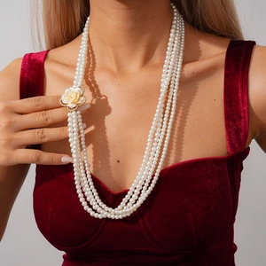 Dettaglio elegante collana di perle multistrato con un accessorio floreale in resina