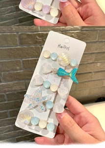 Close-up of ocean-themed hair clips with starfish and mermaid tail charms on card