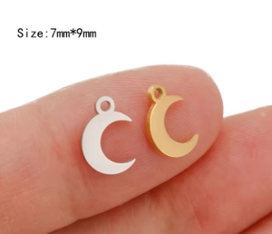 Detail view of 7x9mm gold and silver moon charms displayed on a fingertip for size