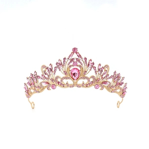 Macro detail of golden tiara featuring pink crystals and teardrop gemstone on white background
